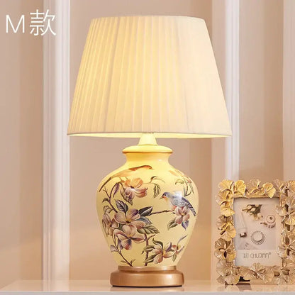 Cream-colored decorbites™ bird flower ceramic table lamp with hand-painted design and pleated off-white shade for bedroom