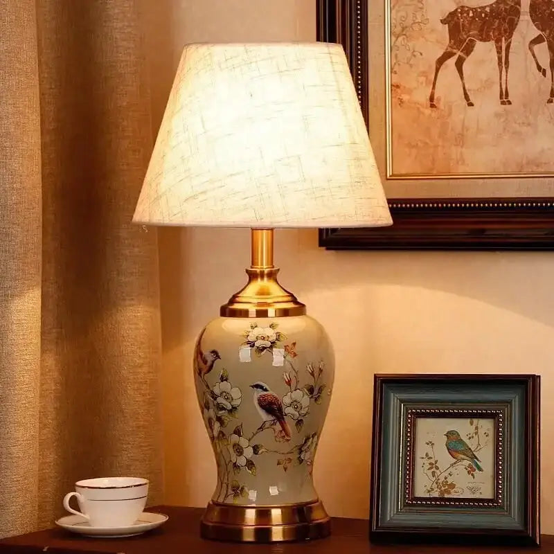 Cream-colored DecorBites™ ceramic table lamp with gold metal accents and hand-painted floral bird motifs for living room
