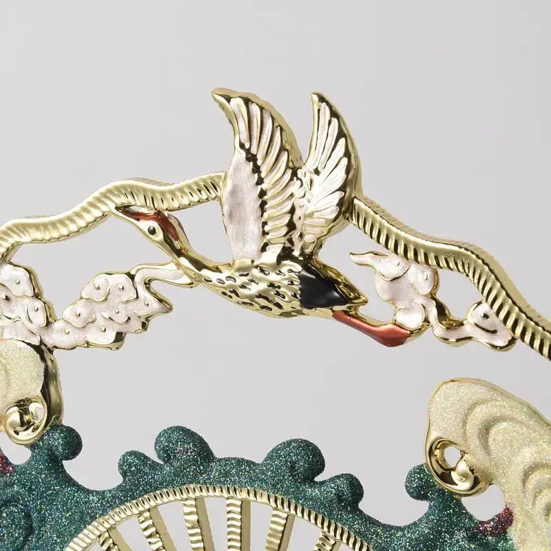 Gold-colored metal decorative crane with white and black accents and ornate clouds on a decorbites chinese ceramic vase for living room decor