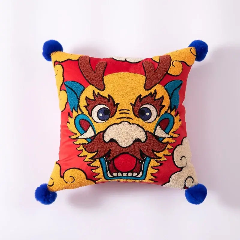 Vibrant red DecorBites™ dragon embroidered cushion cover with yellow brown blue accents and blue pom-poms for festive decor