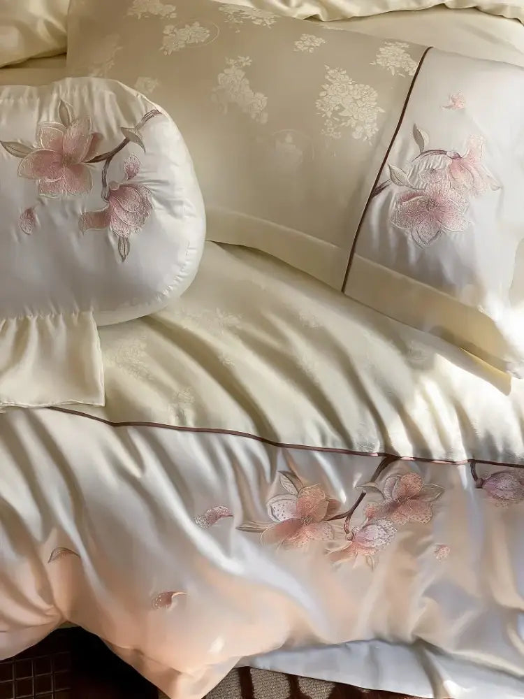Cream-colored satin bedding set with delicate pink floral embroidery and gold-toned piping in decorbites chinese floral lyocell cotton