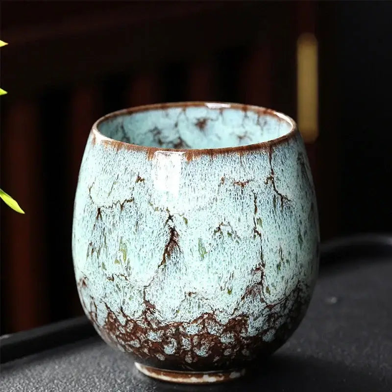 A handcrafted ceramic coffee cup with mottled turquoise and brown glaze and organic crackle pattern from DecorBites™