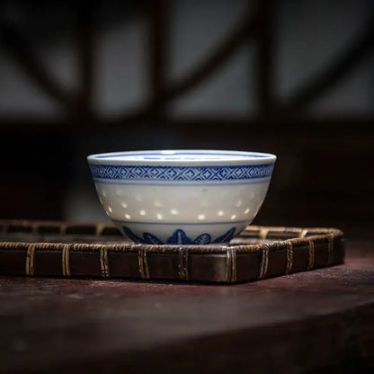 A delicate white porcelain decorbites chinese orchid dragon bowl with blue geometric patterns and a perforated interior