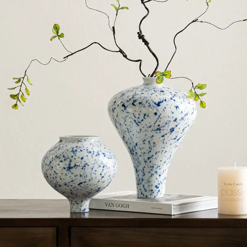 DecorBites™ Chinese retro ceramic vase in white with blue speckles and flared neck holds delicate green branches