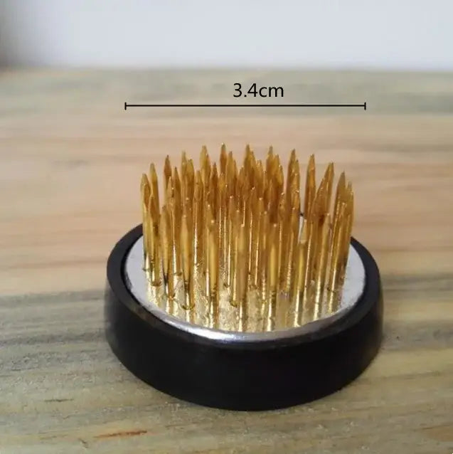 Golden sewing needles arranged upright in a black circular base with a silver inner circle for ceramic flowerpot vase decor