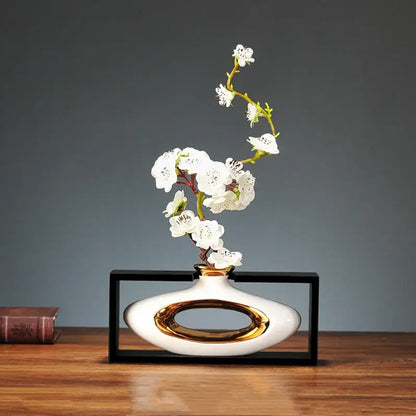 White ceramic vase with gold oval accent holding delicate white blossoms in decorbites chinese style ceramic design