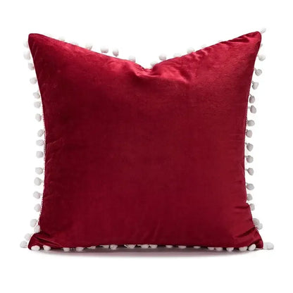 A plush red velvet christmas candy cushion with white pom-poms by DecorBites for festive sofa decor