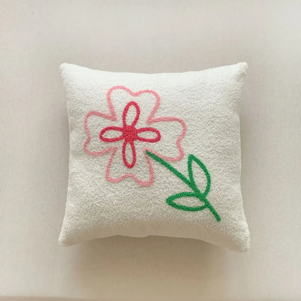 A soft white textured embroidered pillow from decorbites christmas cartoon set featuring a pink flower design