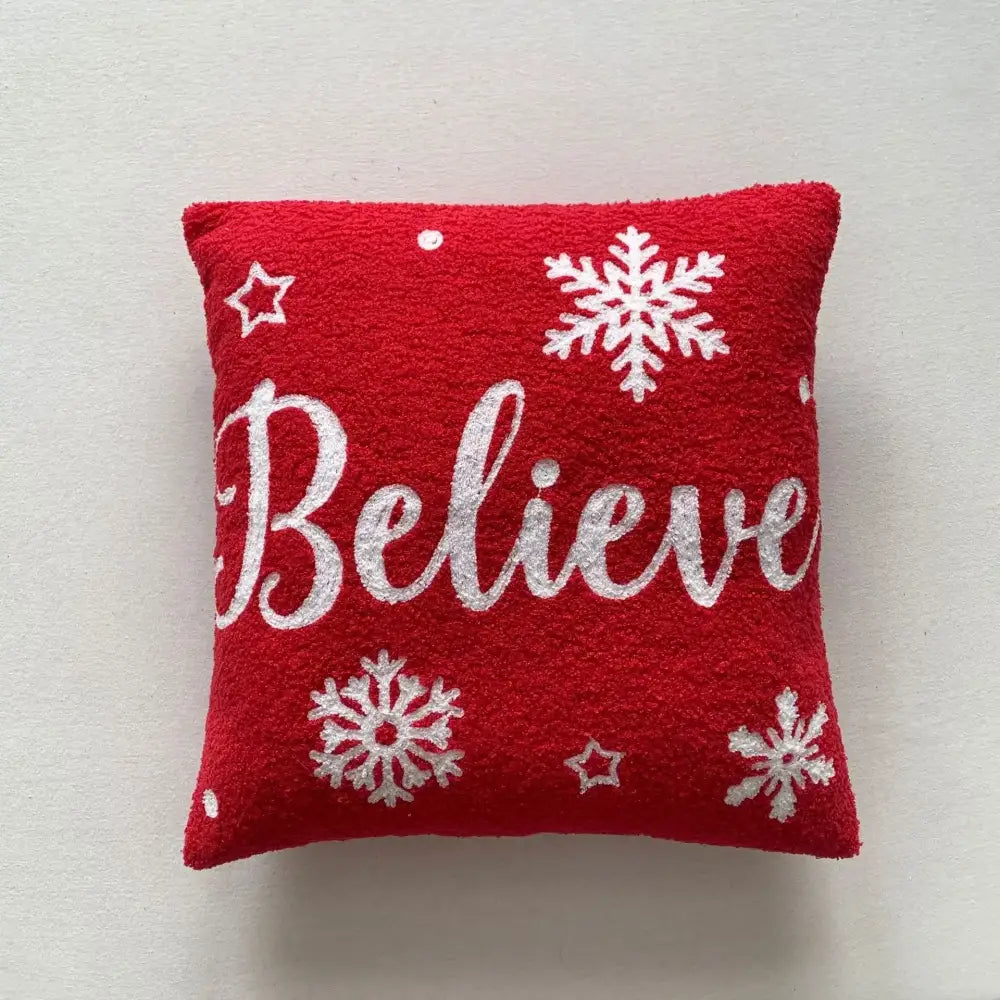 Red plush pillow cover with white embroidered snowflakes and stars featuring believe in glittery silver font for festive decorbites christmas cartoon design