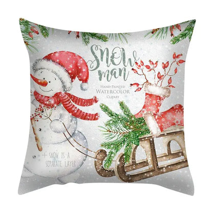 White throw pillow with hand-painted snowman in red santa hat and scarf pulling a sleigh in decorbites christmas cushion set