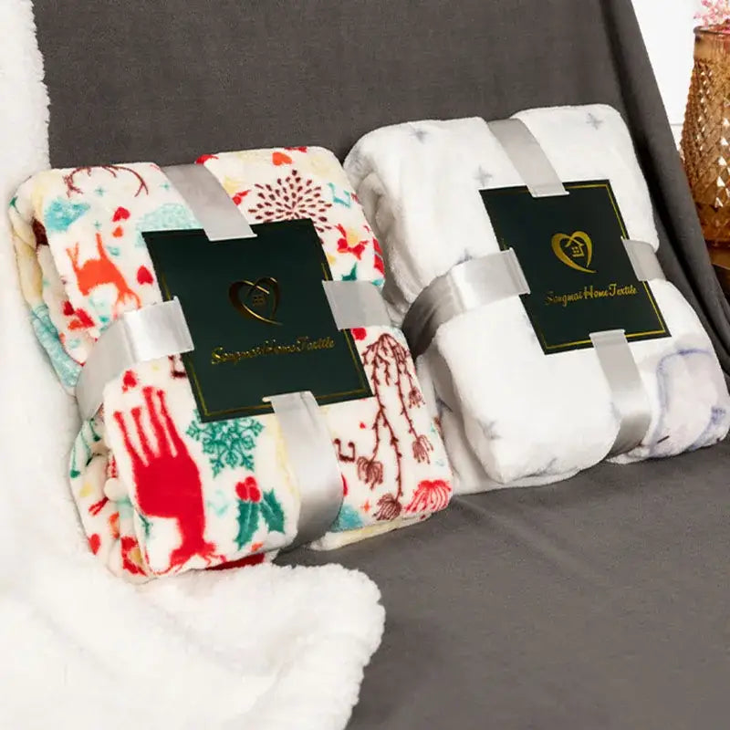 Two decorbites christmas flannel blankets with festive designs in cream and white plush for winter shawl and cushion use