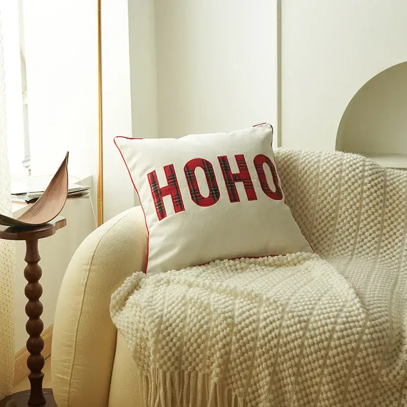 White cushion with red ho ho christmas letter embroidery in plaid pattern and red stitched border from decorbites christmas letter set