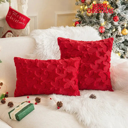 Two vibrant red decorbites christmas plush textured throw pillows with raised star pattern on white fur sofa