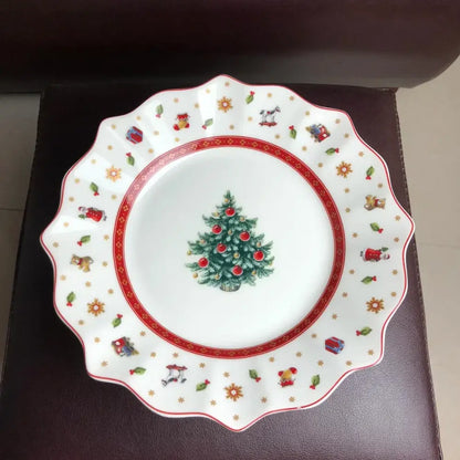 White ceramic plate with scalloped edge featuring decorated christmas tree and festive illustrations in decorbites christmas porcelain tableware set