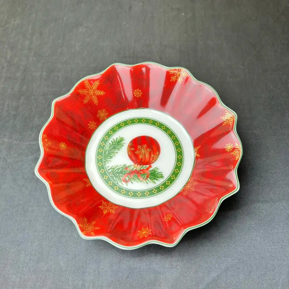 A festive red ceramic dish with scalloped edges and gold snowflakes from decorbites christmas tableware set
