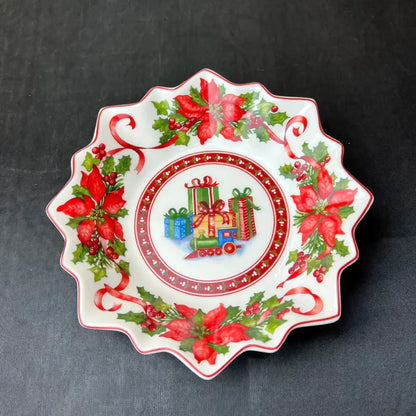 A festive white ceramic dish with scalloped edge decorated with red poinsettias green holly berries and wrapped gifts from decorbites christmas tableware