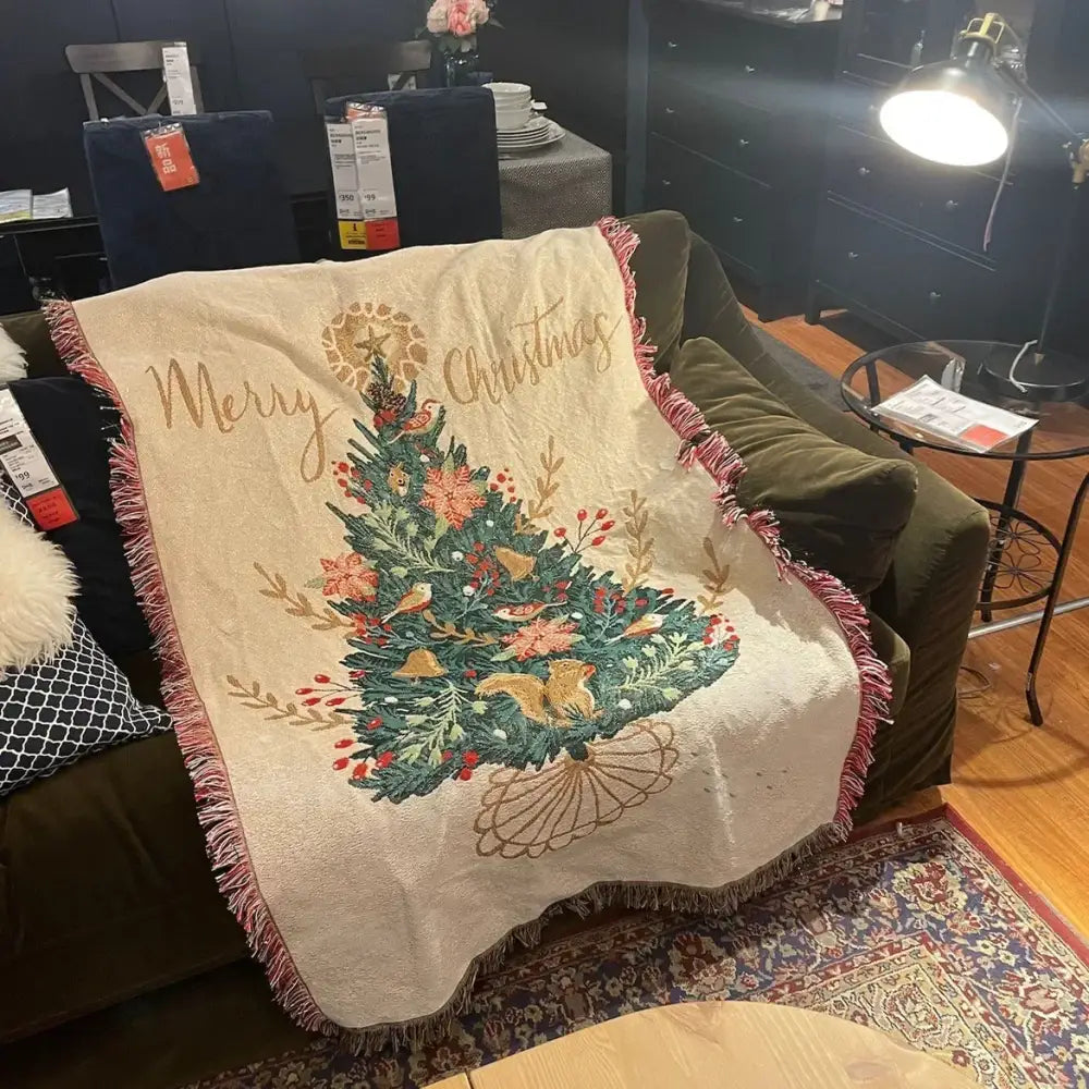 Beige woven decorbites christmas throw blanket with festive embroidered tree red berries gold bells and pink fringe edges