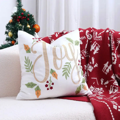 White cushion cover with gold embroidered joy and festive green and orange leaves with red berries for christmas tree decor