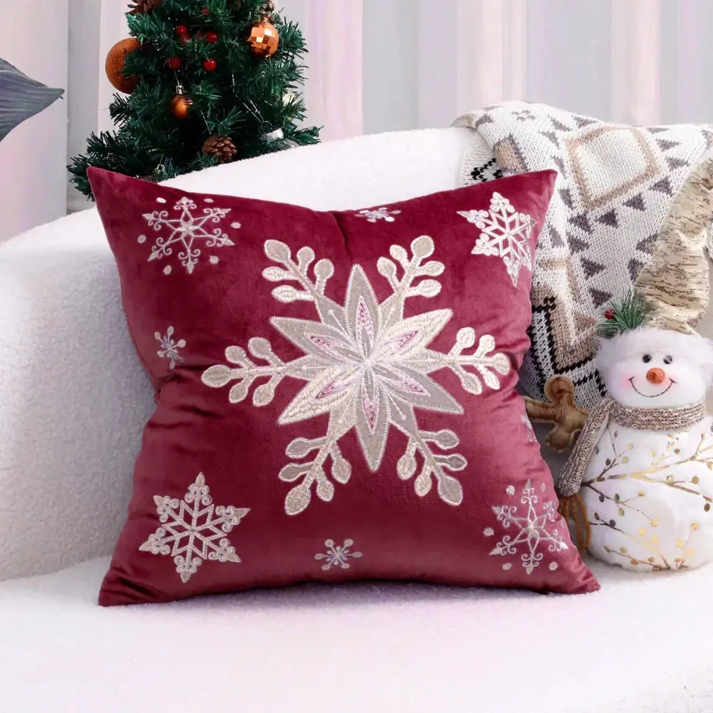 A plush burgundy velvet cushion cover with intricate white and silver embroidered snowflakes for christmas tree decor