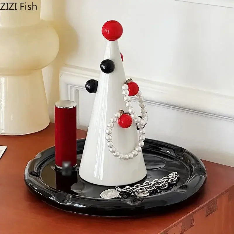 White ceramic DecorBites Christmas tree jewelry stand with red and black accents displaying pearl bracelets and silver chain