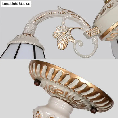 Antique-style porcelain wall sconce with gold leaf accents and floral detailing complementing a multi light chandelier