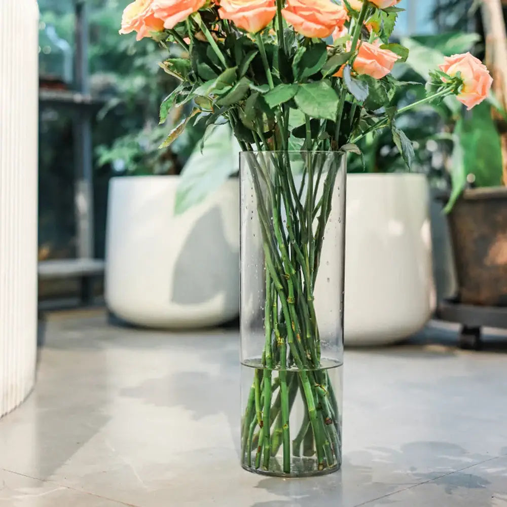 Clear acrylic cylinder vase by DecorBites holding peach-colored roses for weddings in a clear acrylic design
