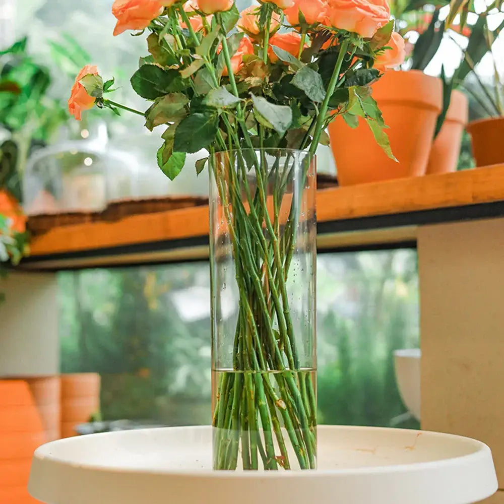 DecorBites™ clear acrylic cylinder vase holding vibrant peach roses with green stems for elegant weddings