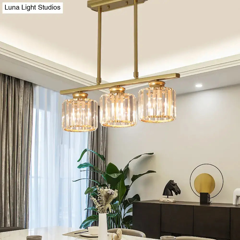 Brass-finished DecorBites clear crystal island light with three cylindrical glass shades for elegant dining room hanging