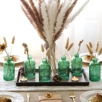 Set of six emerald green clear glass bud vases with embossed circular patterns on a dark tray from DecorBites™