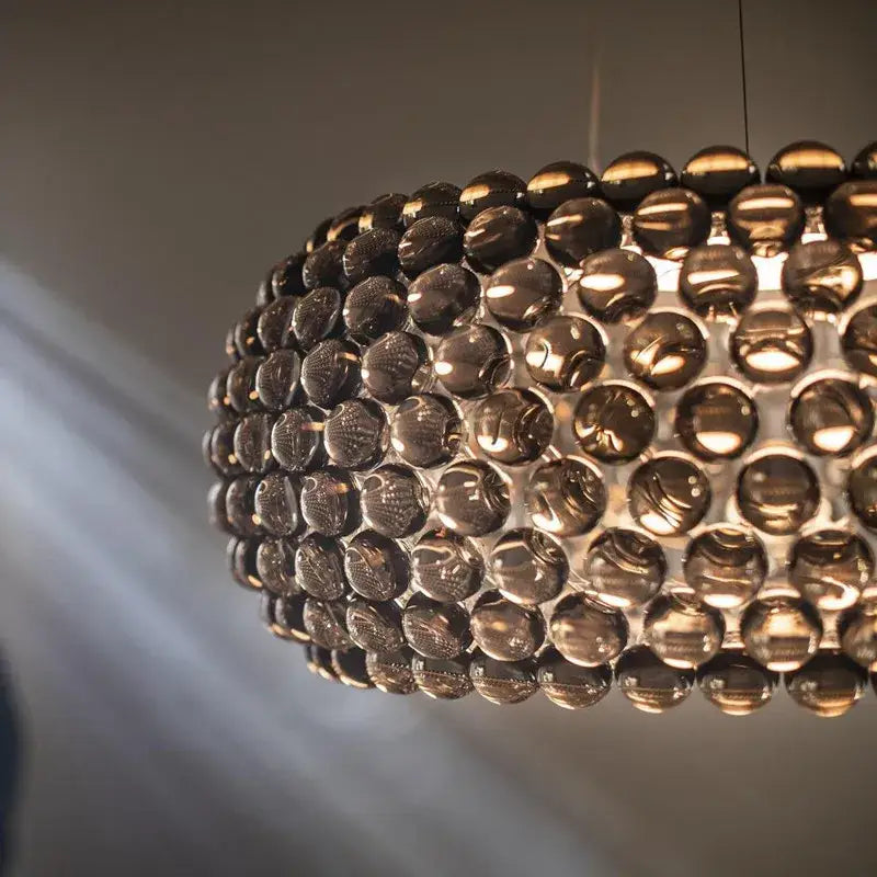 A modern spherical pendant light with polished dark amber glass orbs in decorbites clear gold acrylic finish