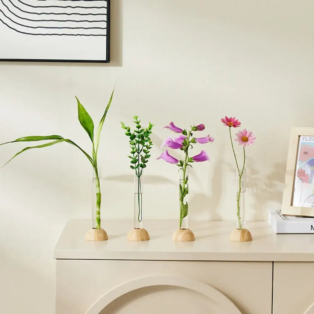 Four clear plastic test tube vases with wooden bases holding various plants for decorbites home decor display