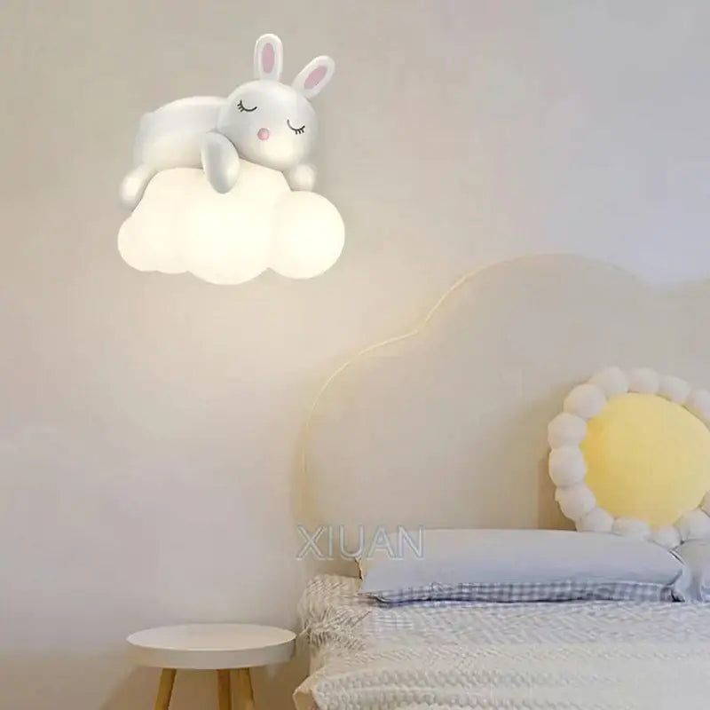 Decorbites cloud bunny lamp is a white rabbit-shaped wall light with closed eyes pink nose resting on a soft cloud base