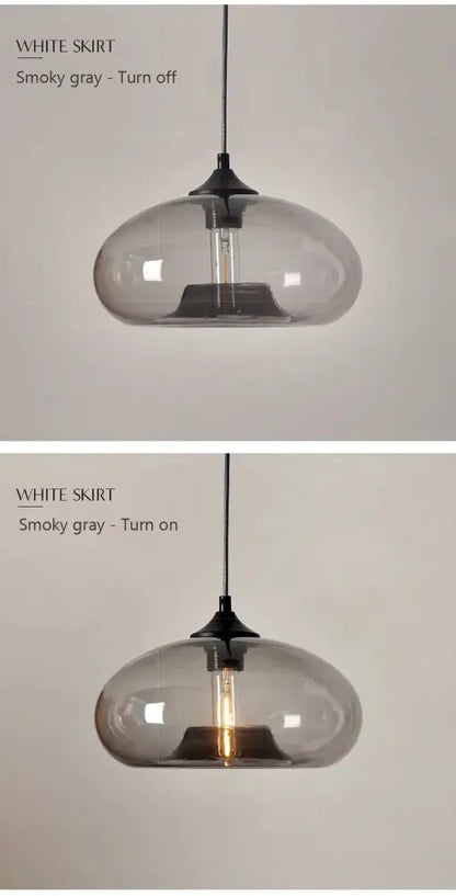 A sleek smoky gray glass colorful led pendant light with black metal fixture and exposed filament bulb for restaurant use