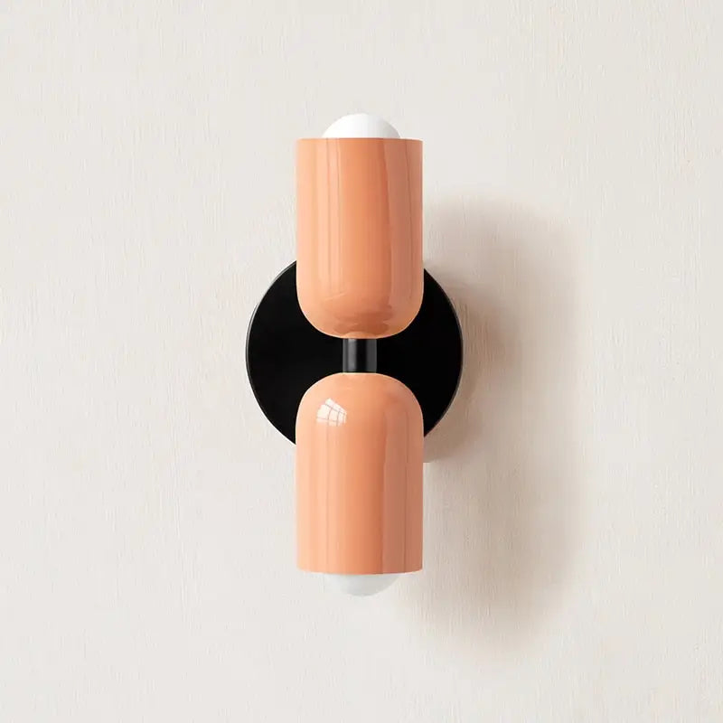 Coralbcolored modern wall sconce with glass shade white spherical accents and black circular base by decorbites