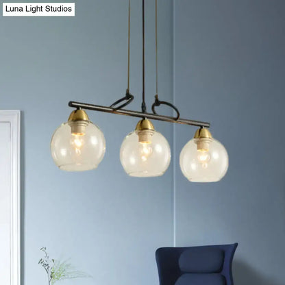 Modern three-light black pendant chandelier with clear prismatic glass and brass accents for dining hall lighting