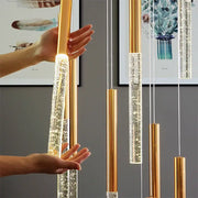 Gold-toned cylindrical pendant lights with clear crystal tubes and warm led bulbs in contemporary crystal chandelier decorbites for staircase