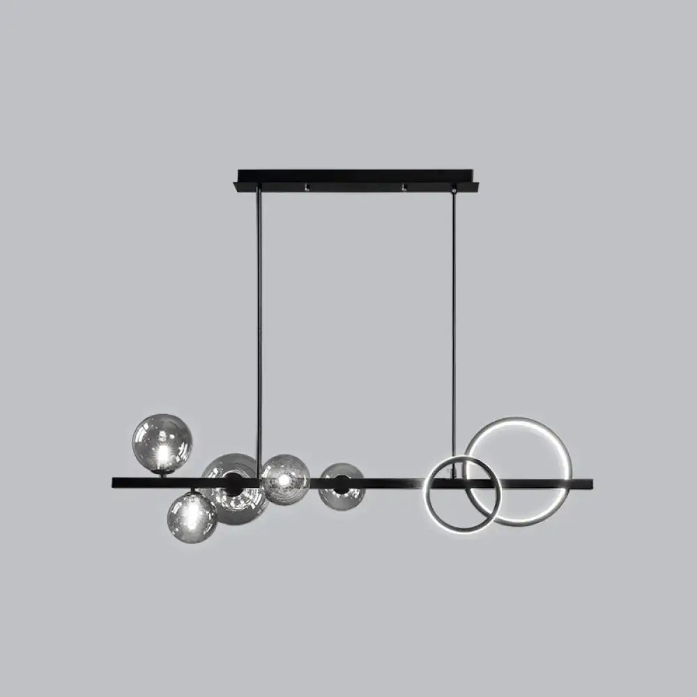 Modern black metal island lamp with sleek horizontal bar, hanging smoke grey glass spheres, and glowing circular rings