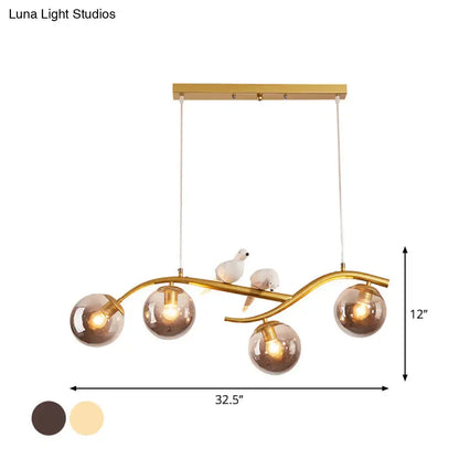 Gold-toned metal branch pendant light with four smoke grey cognac glass globes and two white ceramic bird figurines