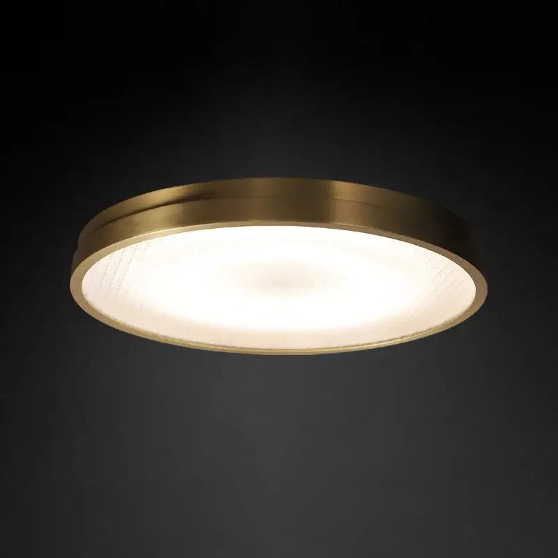 A modern circular ceiling lamp with brushed brass copper frame and frosted glass diffuser for bedroom lighting