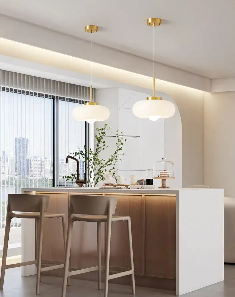 Two DecorBites™ copper pendant light fixtures with gold-finished metal and frosted glass shades hanging from ceiling
