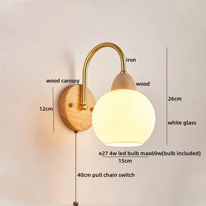 A warm-toned decorbites cotton led wall lamp with brass iron arm wooden base and frosted glass globe for bedroom use