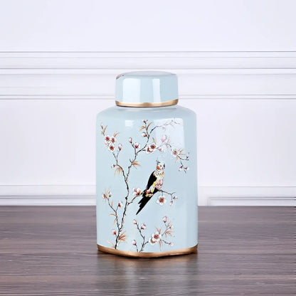 A light blue decorbites country ceramic tea canister with gold trim hand-painted cherry blossoms and perched bird design