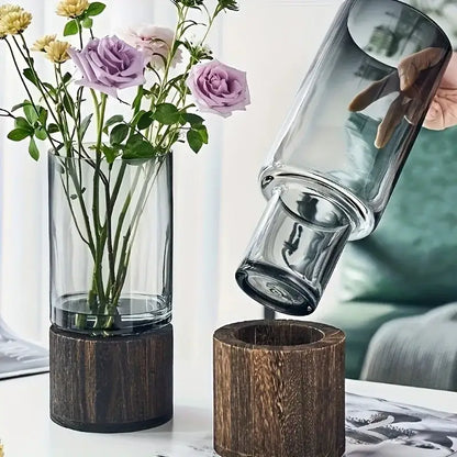 Tall clear creative retro glass vase with dark wood base holding purple and yellow roses for living room decor