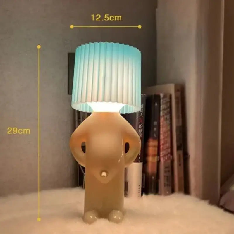 A creative table lamp by decorbites shaped like a beige translucent cartoon figure with a blue to white pleated shade