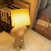 Beige whimsical figurine creative table lamp with pleated yellow shade ideal for bedside reading and children’s rooms