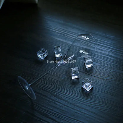 A decorbites crystal champagne flute with a long stem and wide bowl lies on its side among clear ice cubes