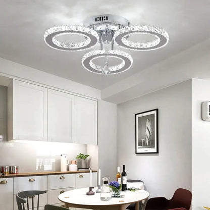 Modern chrome-finished decorbites crystal chandelier with three interlocking crystal rings and central pendant light