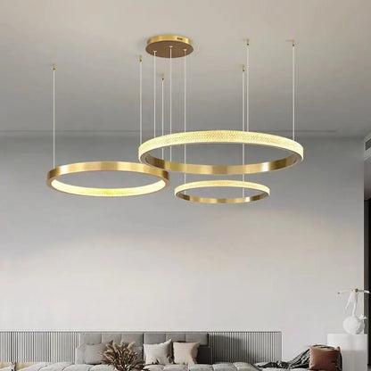 Modern gold-toned circular decorbites crystal chandelier with illuminated rings for luxury living and dining rooms