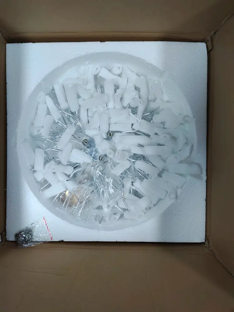 White plastic and metal components of decorbites™ crystal chandelier lamp package arranged for living room use