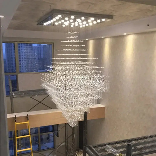 A modern multi-tiered decorbites crystal chandelier with cascading glass elements and square ceiling fixture for living rooms and lobbies
